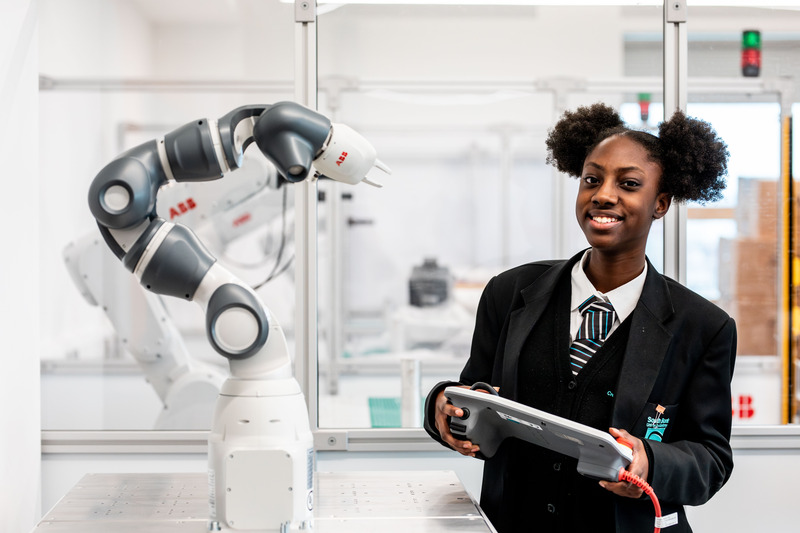 Smiling student controlling robotic arm