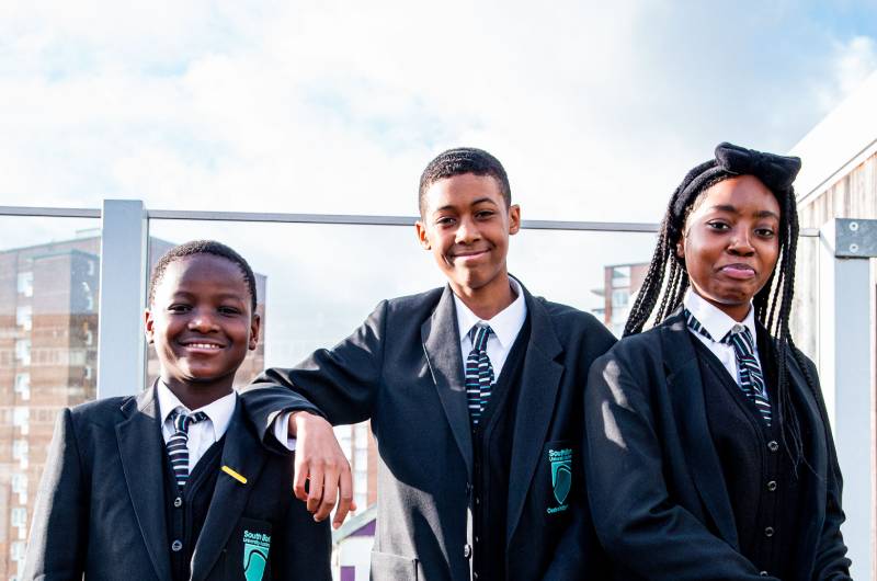 Three students smiling in outdoor area