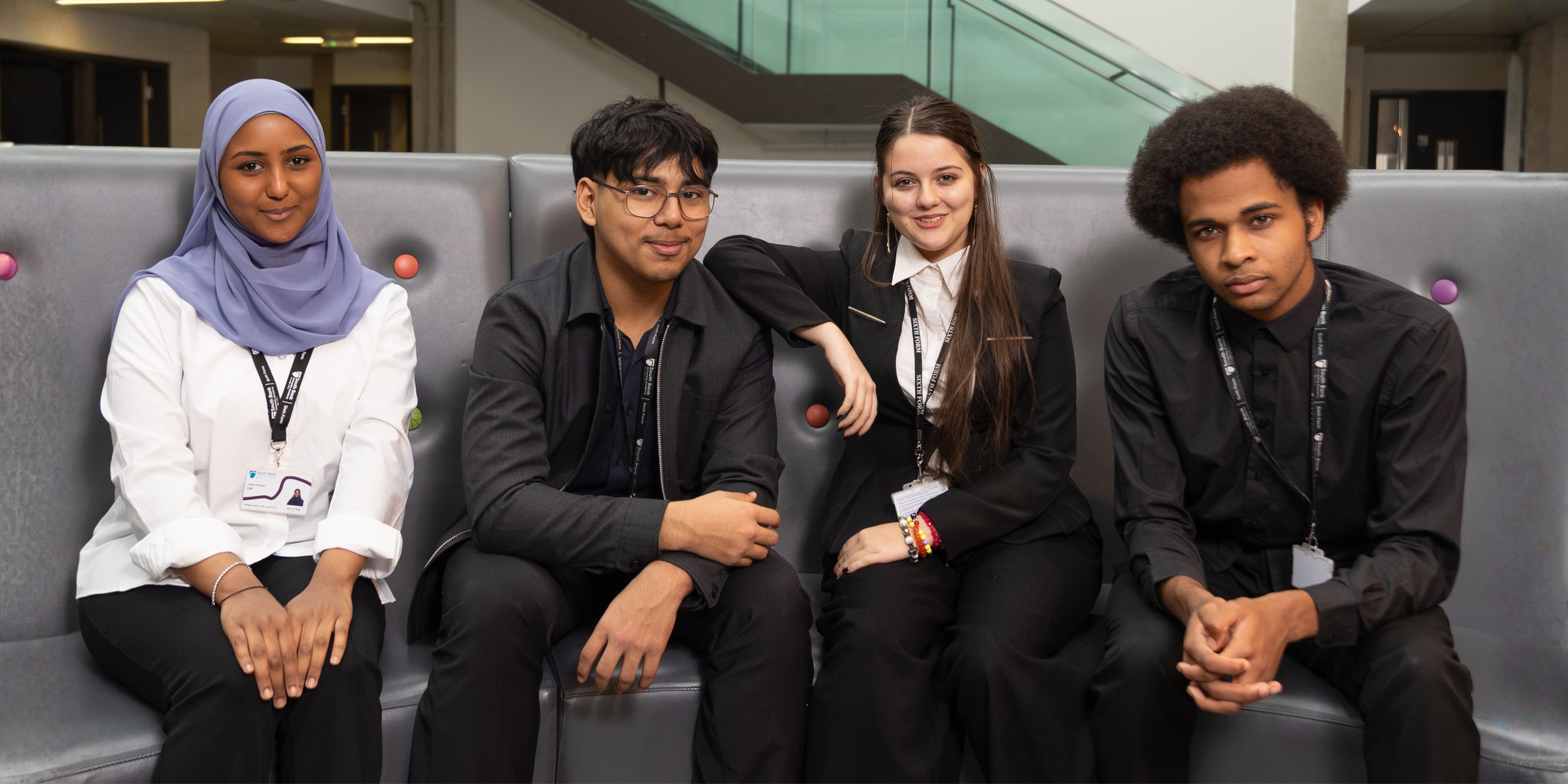 Four students smiling and sitting next to each other